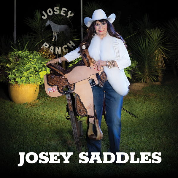 A woman in a cowboy hat poses with a saddle at Josey Ranch.