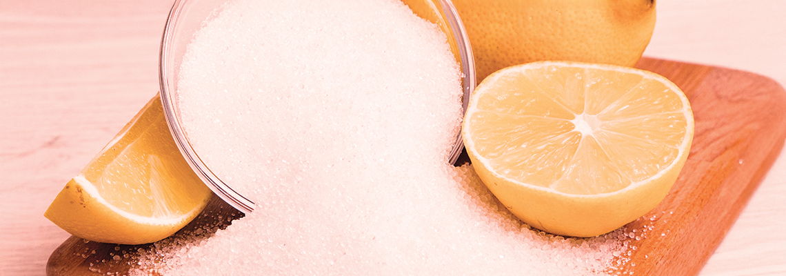 Sugar and lemon slices on a wooden cutting board.