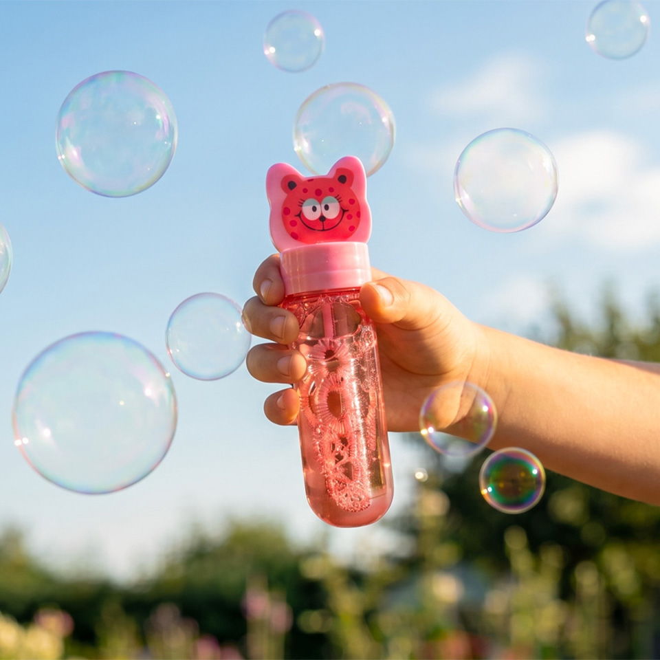 Hand holding a bubble wand with bubbles in the background.