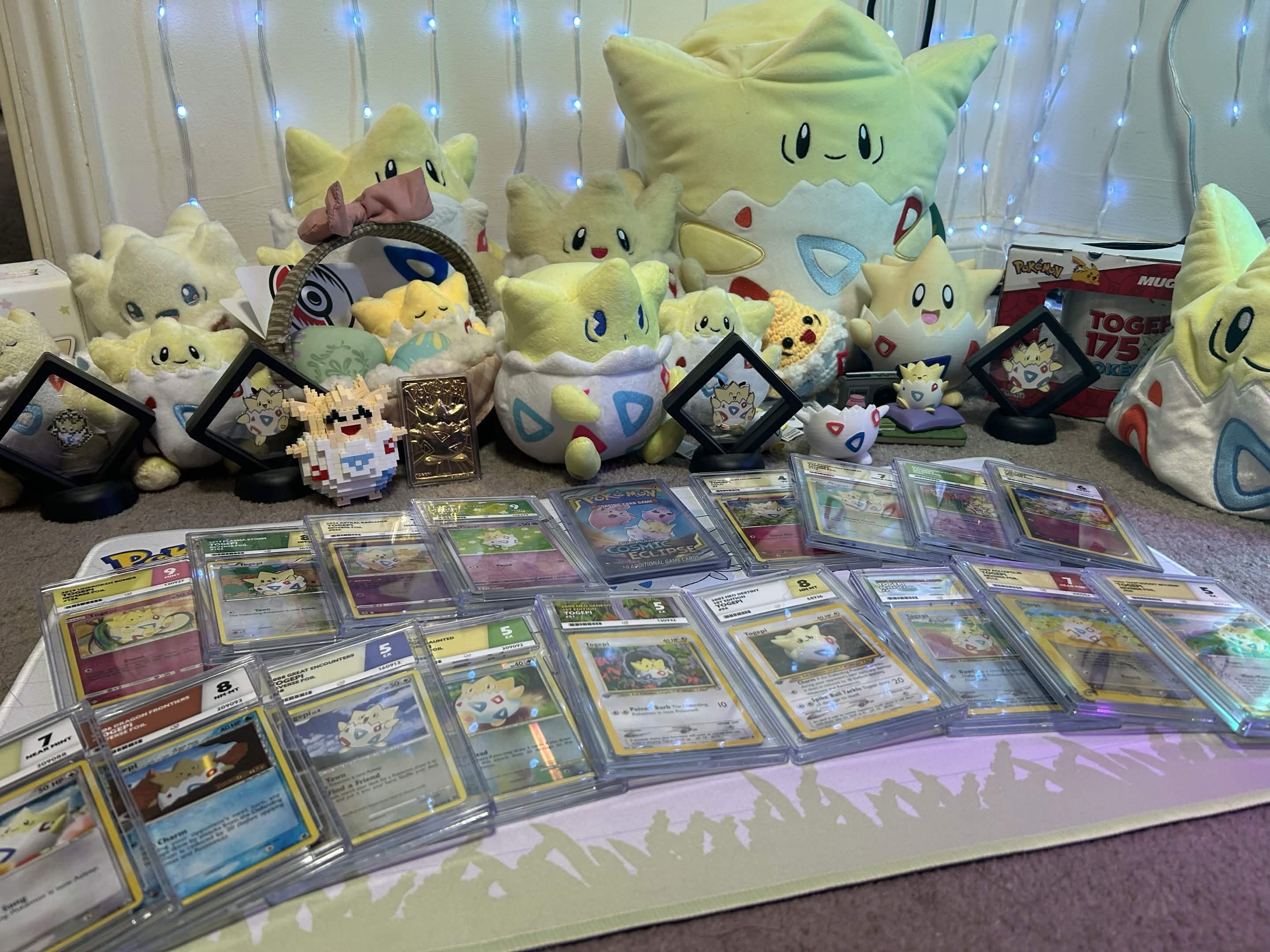 Collection of Pokémon cards and plush toys displayed on a carpet.