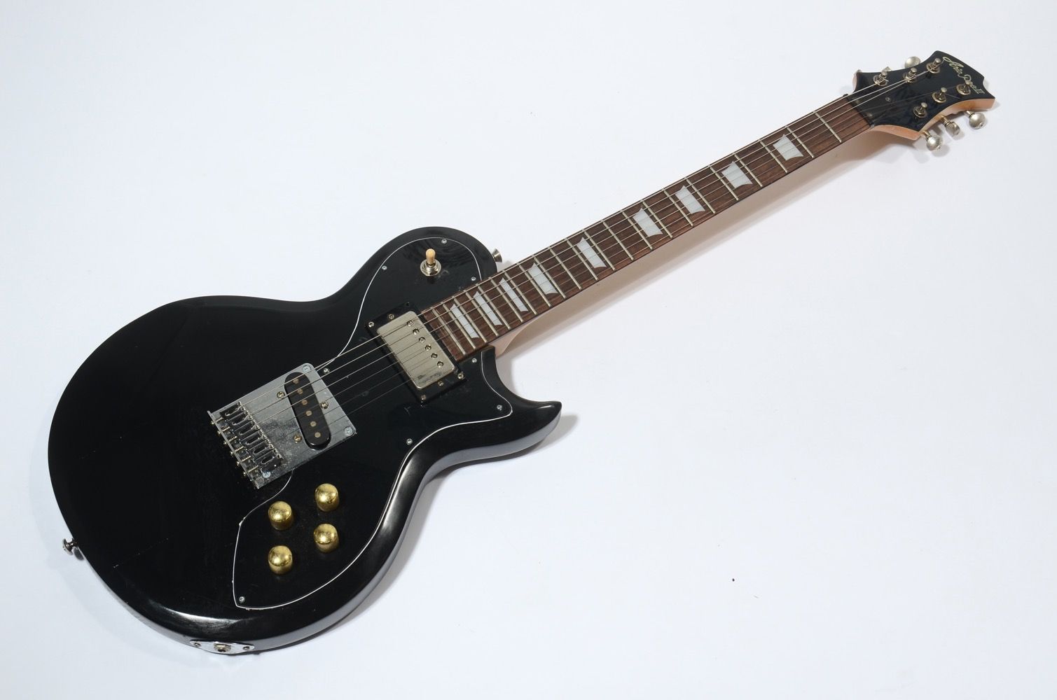 Black electric guitar lying on a white surface.