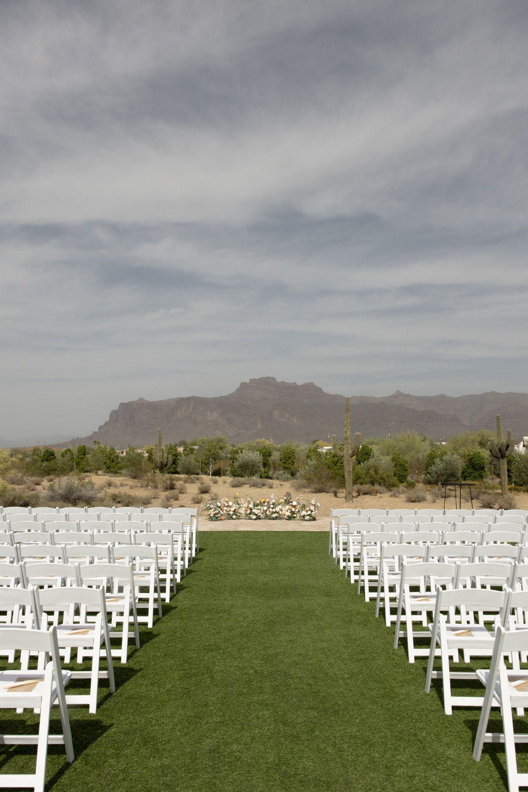 Outdoor wedding venue with white chairs and a mountainous backdrop.
