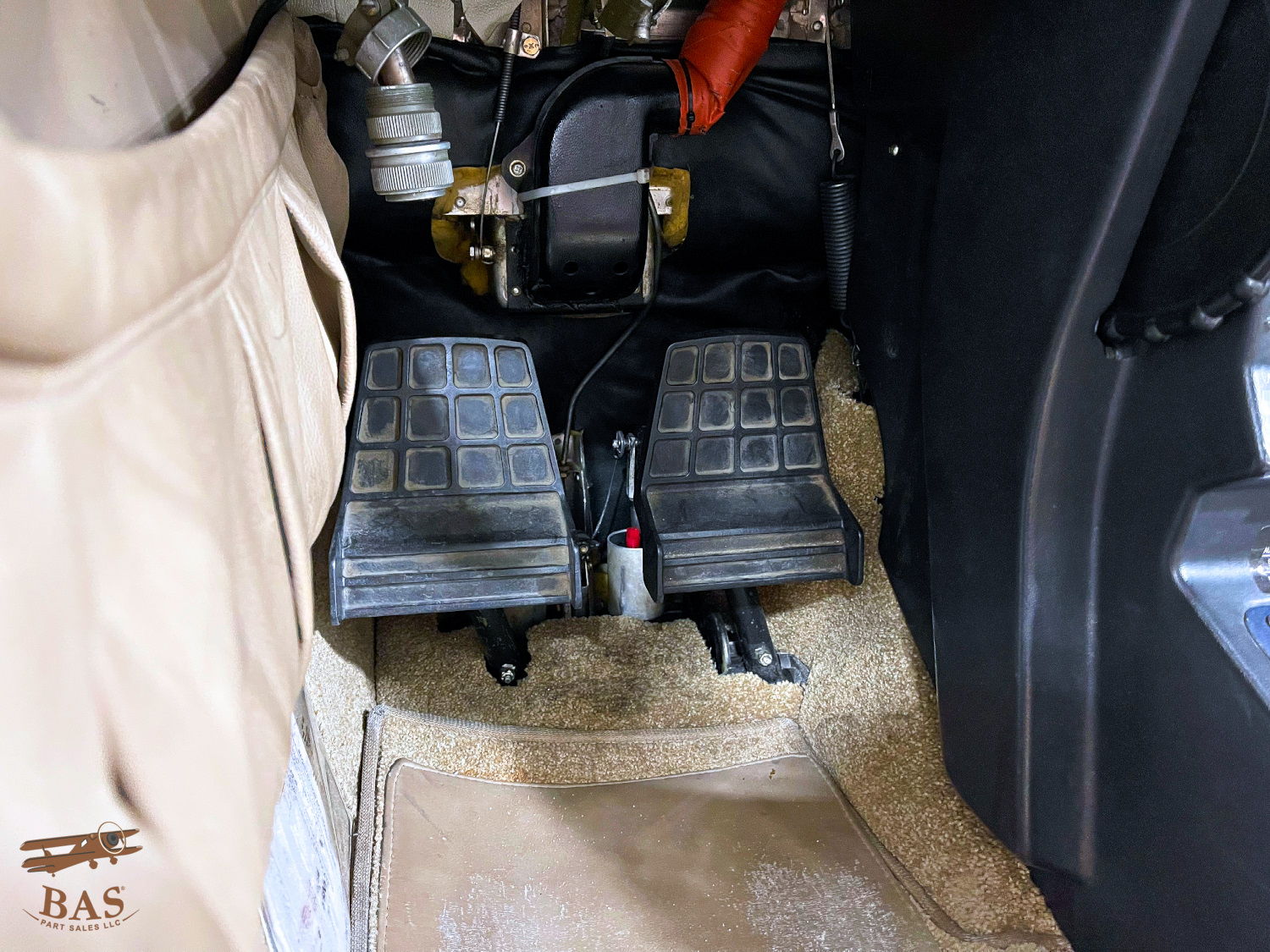 Foot pedals inside a vehicle with a beige interior.