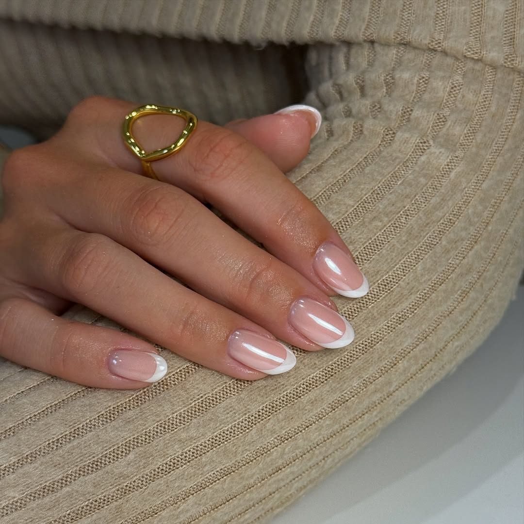 A hand with manicured glazed French tip nails. 