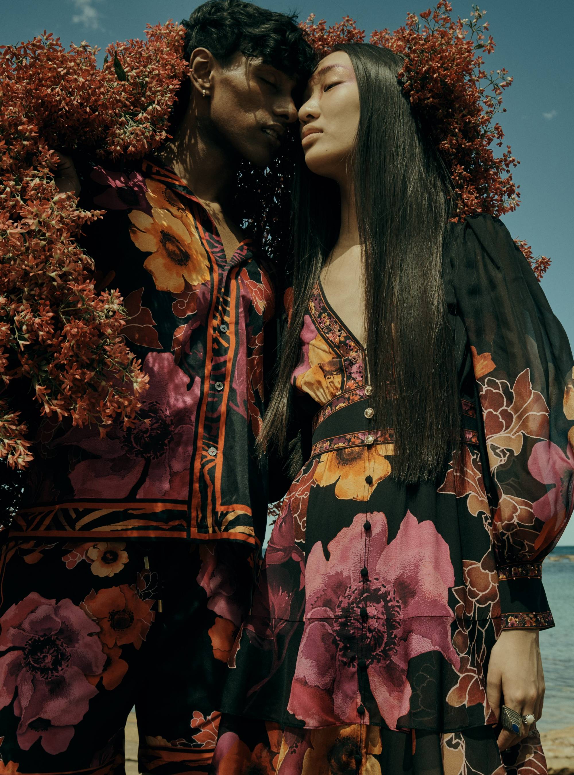 male and female model wearing new season CAMILLA midnight poppy print black outfits with fluro pink and orange flowers