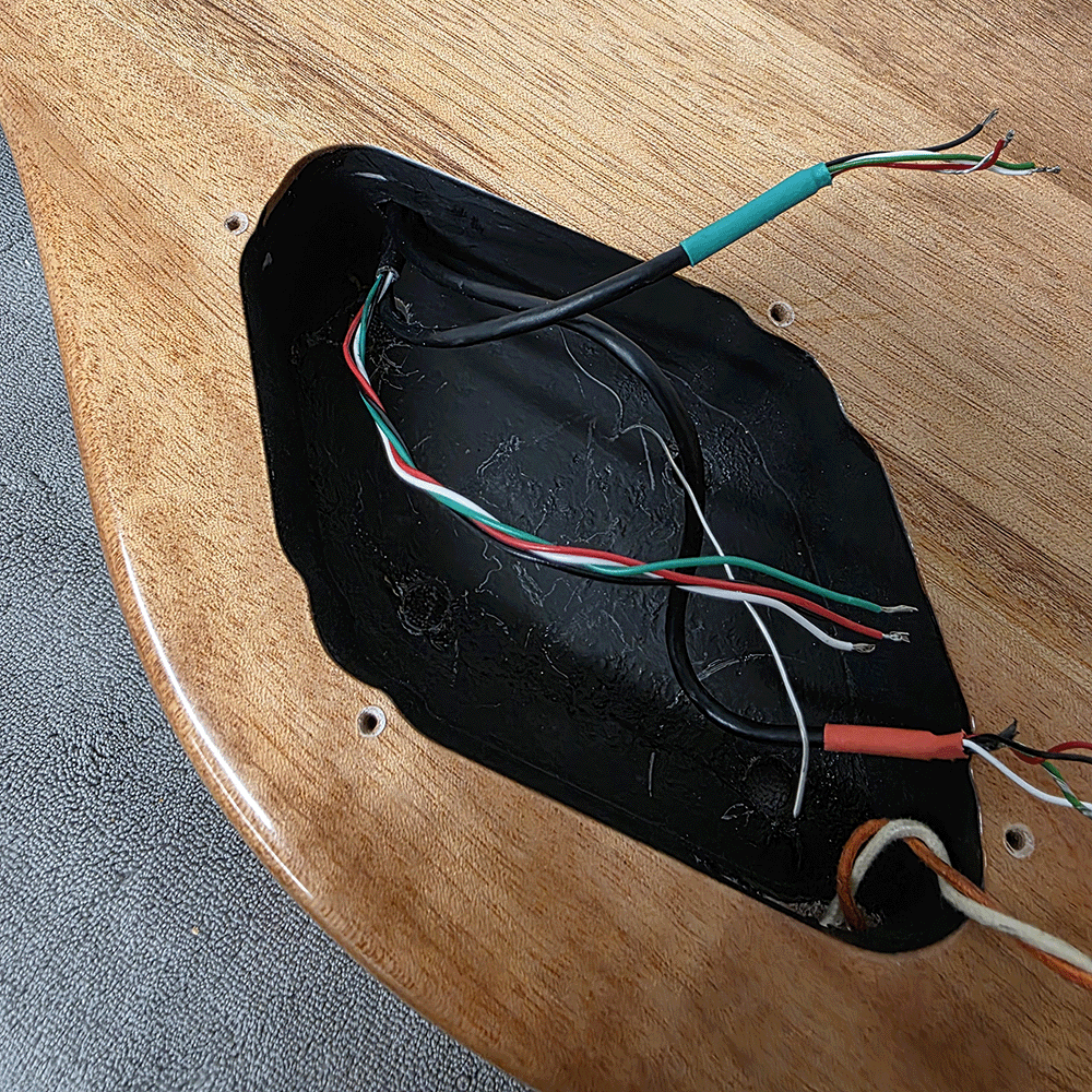 Black electronic component with exposed wires on a wooden surface.