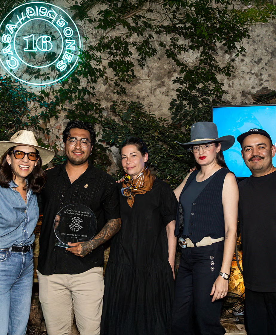 Group of people posing with an award in a garden setting.