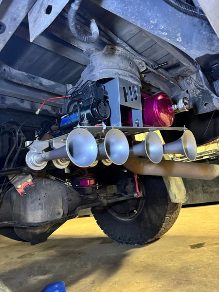 Overhead view of HornBlasters compressor, pink air tank, and five silver train horns on rear axle