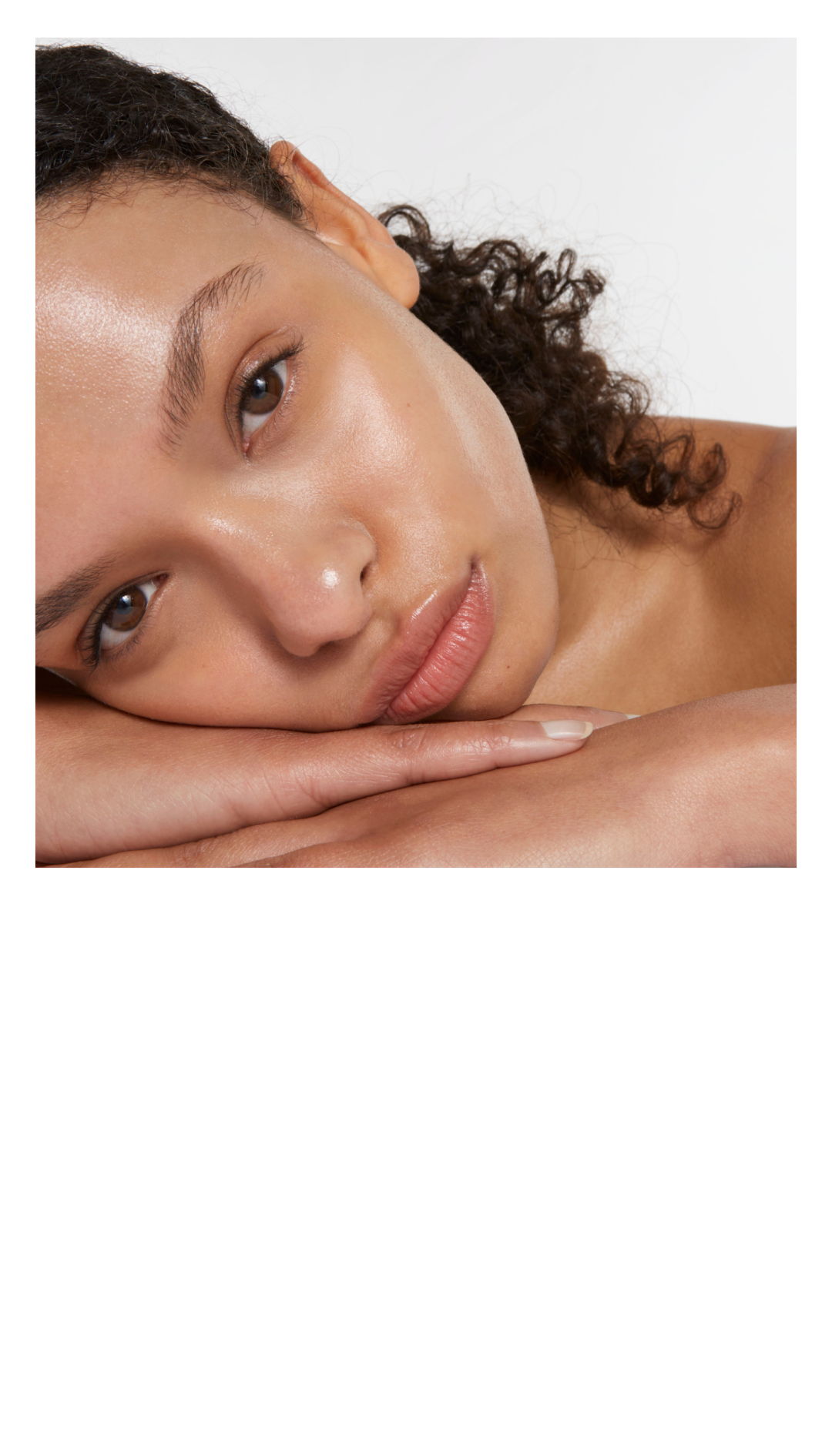 Close-up of a woman resting her chin on her hands, looking directly at the camera.