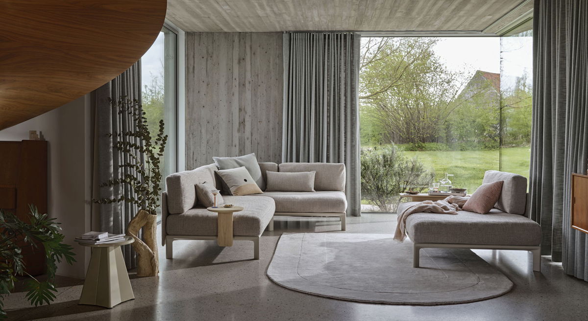Modern living room with Anagram sofa by vitra, large windows and garden view.