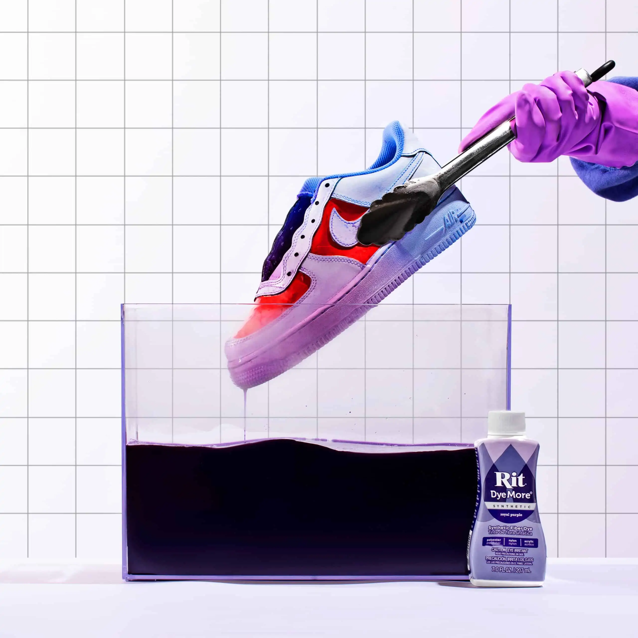 A sneaker being cleaned in a container with purple liquid.