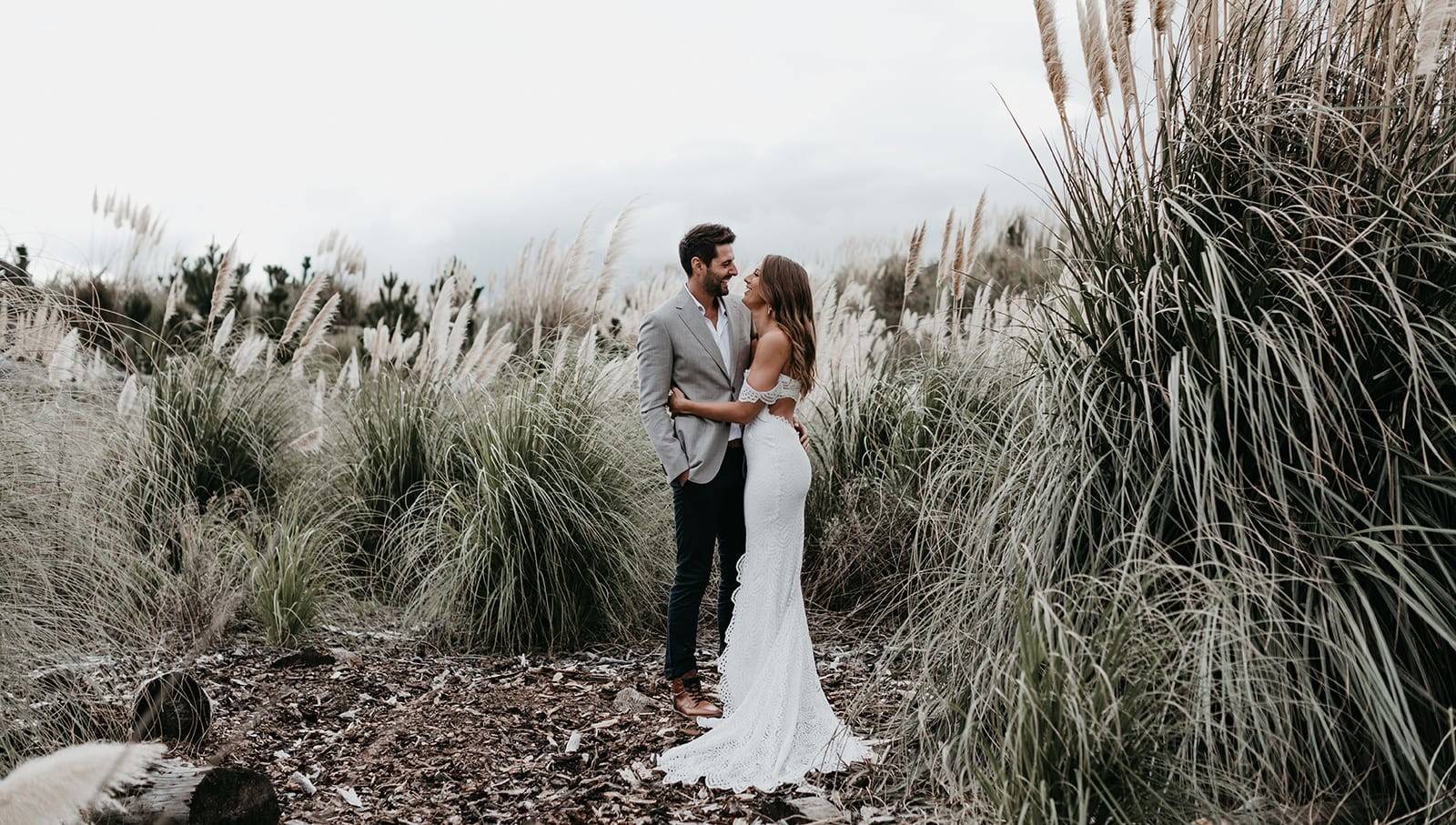 Bride and groom hugging in a grass field