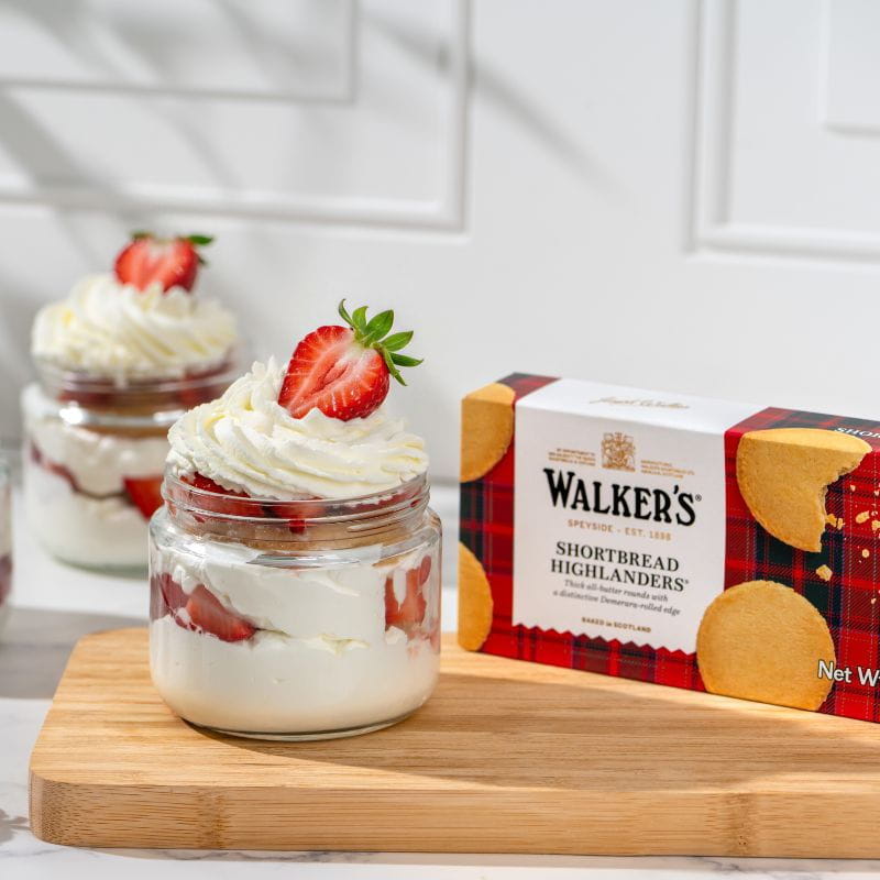 Dessert in a jar with whipped cream and strawberries, alongside a cookie box.