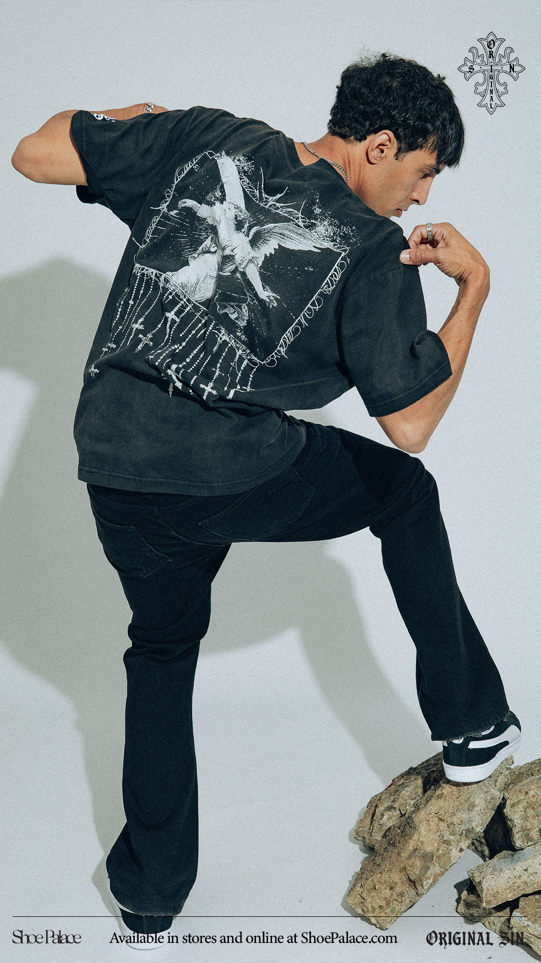 Person posing in a black shirt with graphic design, standing on a rock.