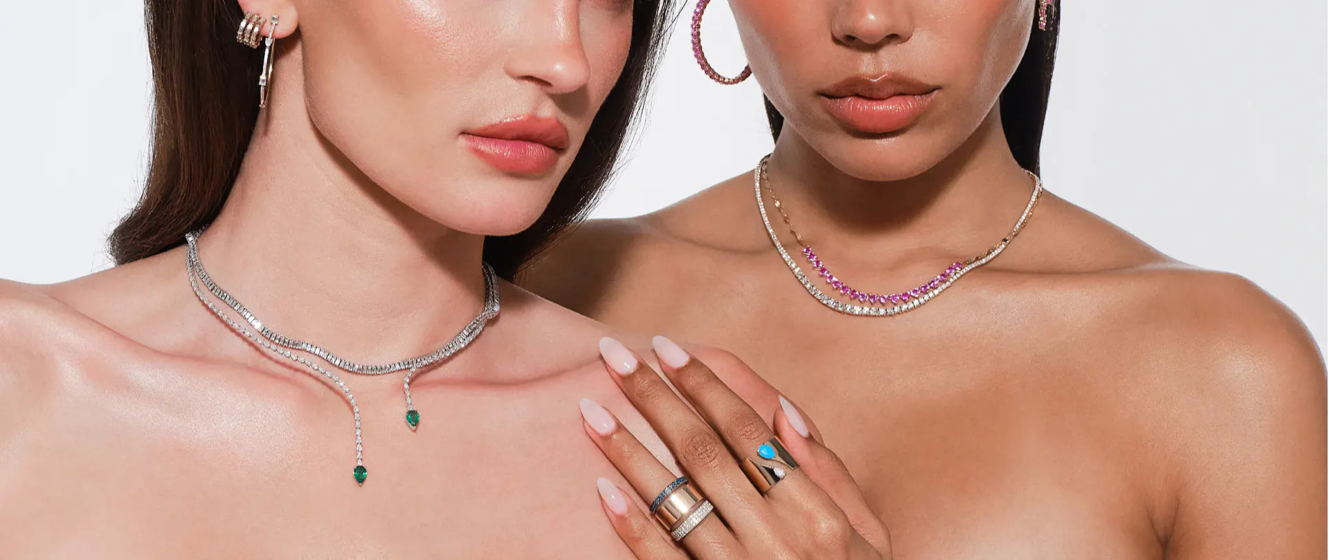 Two women showcasing jewelry, one in a white top, the other in pink.