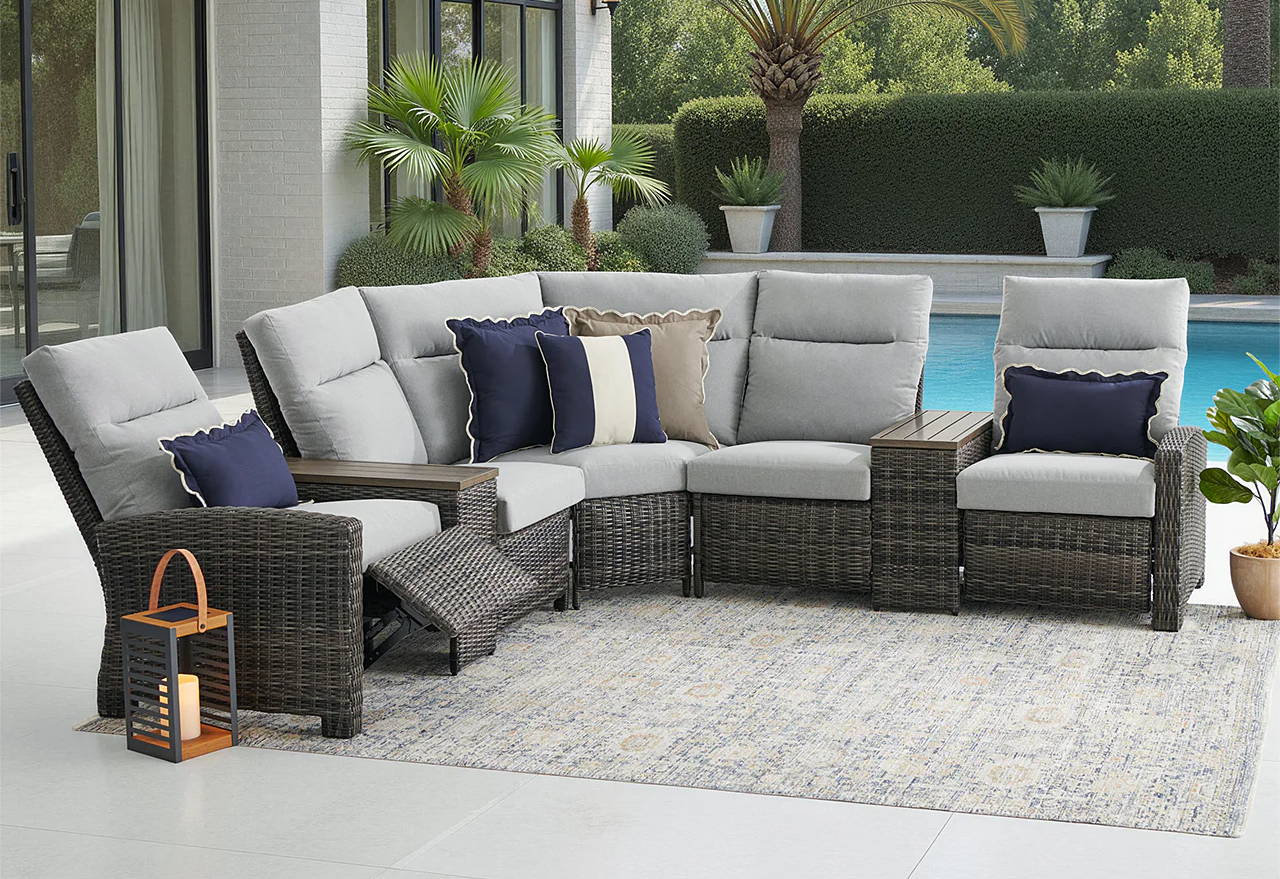 Outdoor patio furniture set near a pool with palm trees in the background.