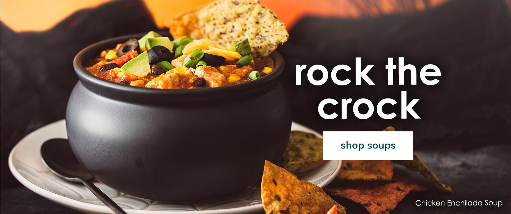 Chicken Enchilada Soup in a black crock with tortilla chips and a “Shop soups” button.