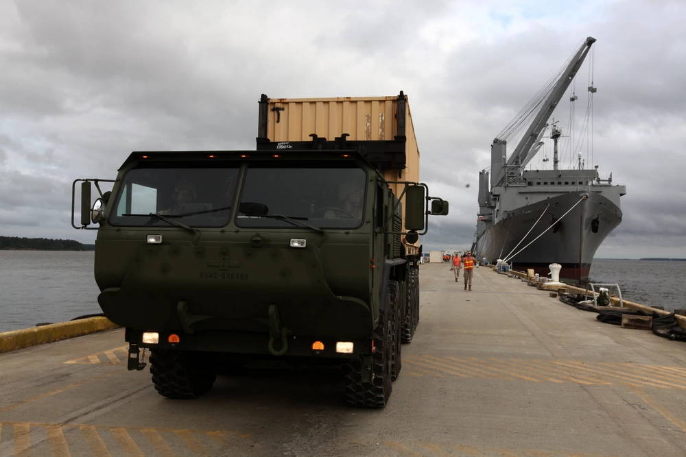 U.S. Marines from Combat Logistics Battalion 8, Transportation Support Company, guides a Logistics Vehicle System Replacement carrying an ISO container during the Expeditionary Logistics WarGame, on Naval Weapons Station Norfolk-Cheatham Annex, Va., June 14, 2012. The purpose of the ExLog WarGame is to build, sustain and enhance the Marine Corps interoperability with their sister services in addition to increasing proficiency in their military occupational specialty.