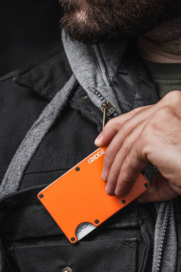 man holding a Basecamp Orange Ridge wallet in the chest