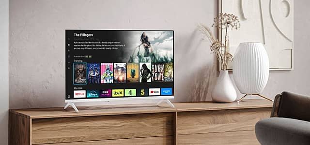 A modern TV displaying streaming apps on a wooden console table.