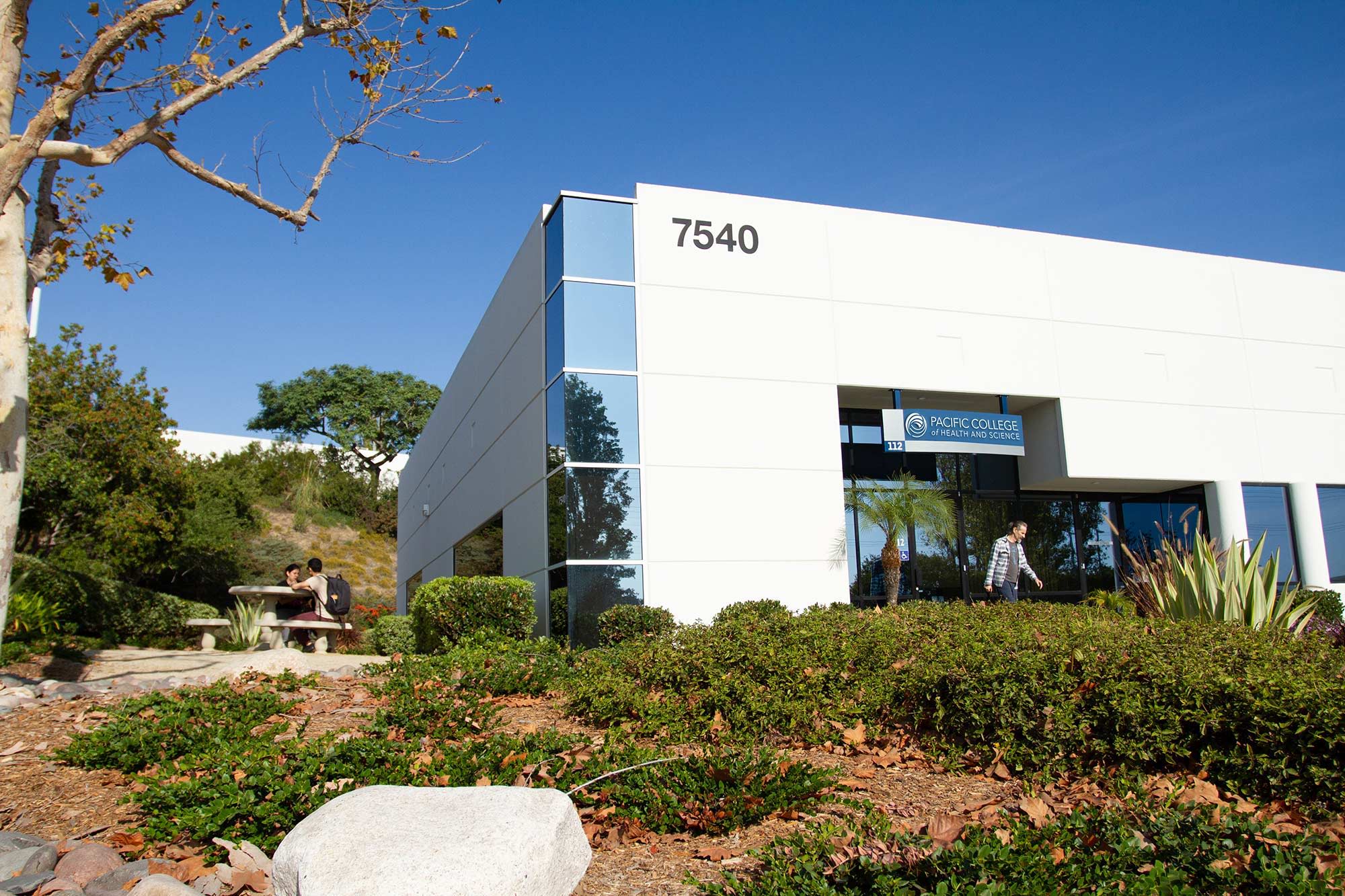 Modern building exterior with landscaping and clear blue sky.
