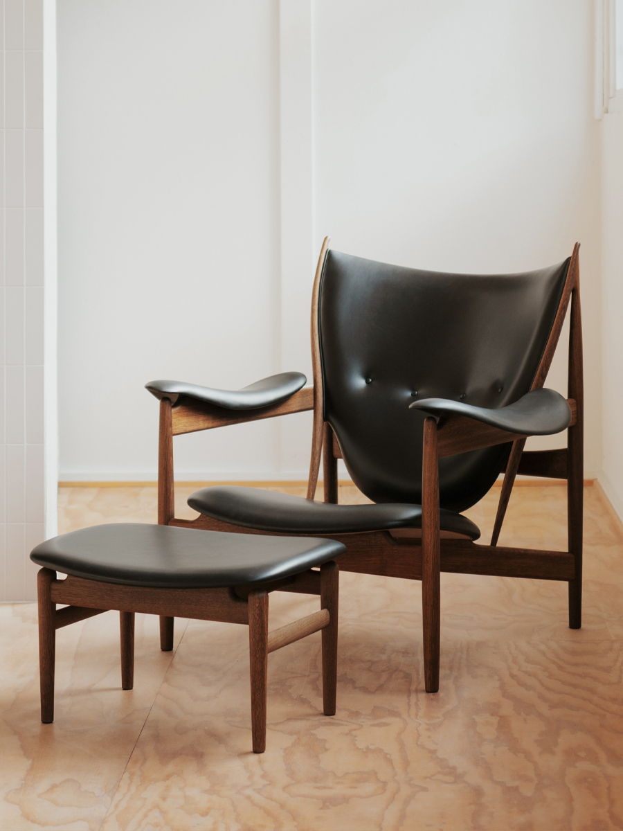 A modern black leather HOFJ chair with an accompanying footrest.