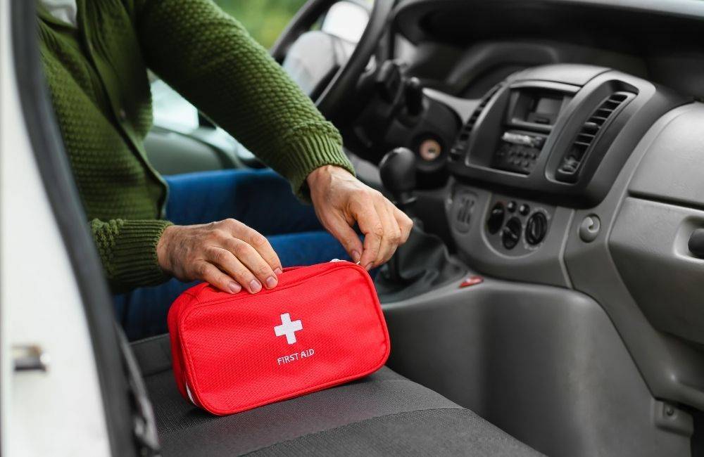 Person opening a first aid kit in their car because it's important to have a safety kit while traveling on the road