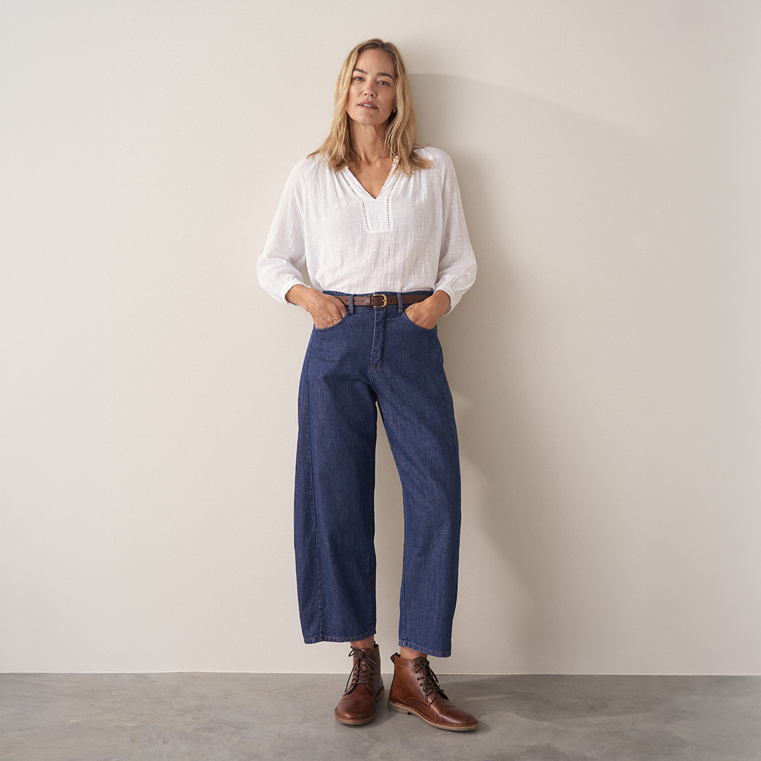 Woman wearing blue cotton denim trousers with brown lace up shoes and a white cotton top