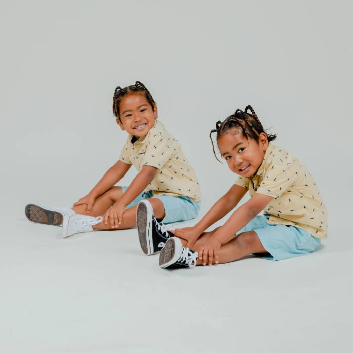 two young boys sitting wearing converse