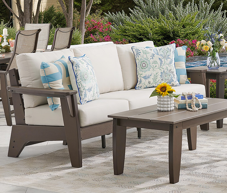 Outdoor seating area with a sofa, cushions, and coffee table.