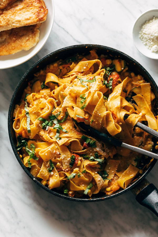 Pappardelle pasta, chicken, zucchini and corn combined in a tomato sauce and served in a bowl