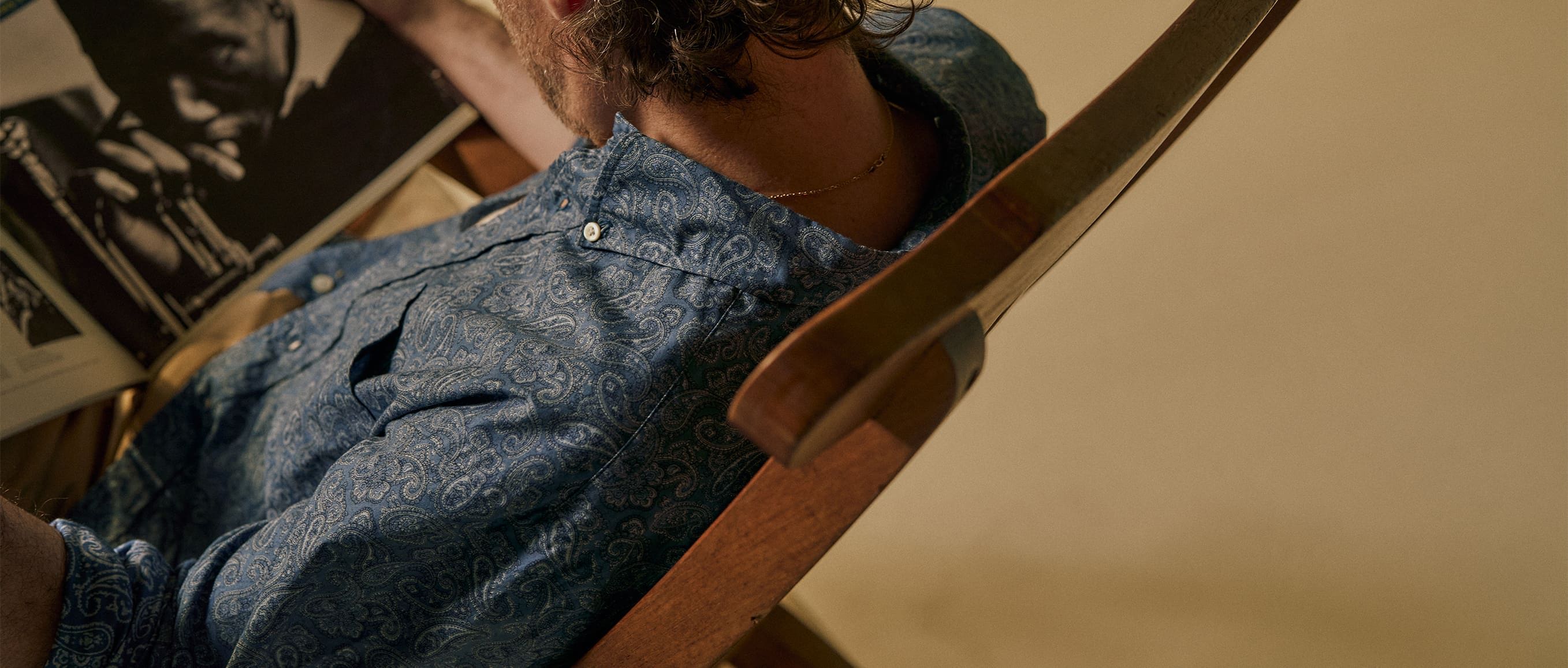 Person sitting in a chair, looking at a photograph or artwork.