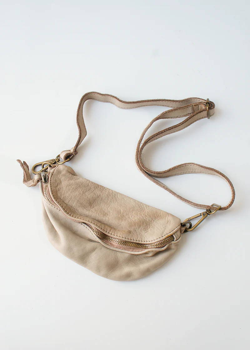 A cream coloured leather bum bag with a bronze zip