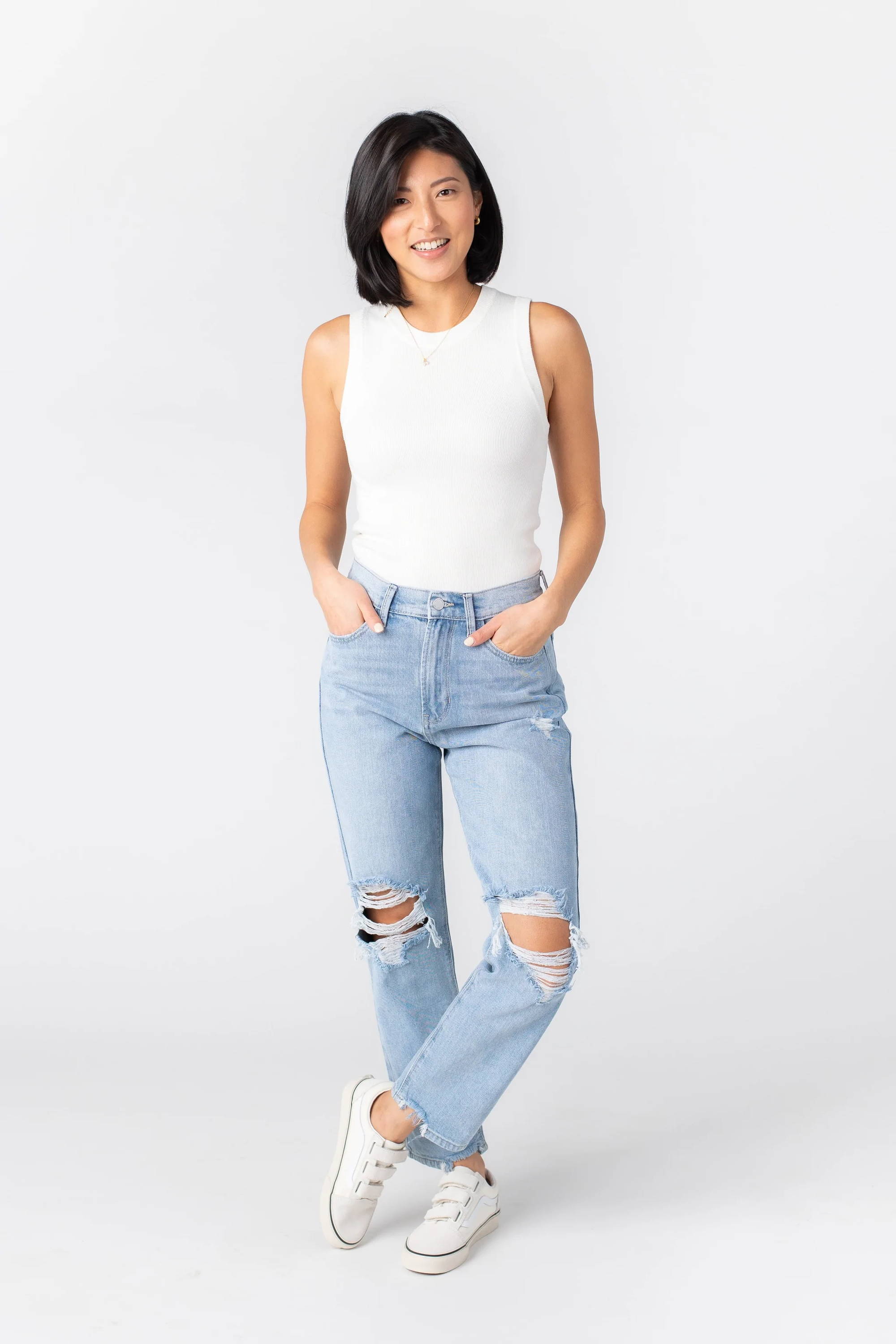 A woman poses in distressed straight-leg jeans