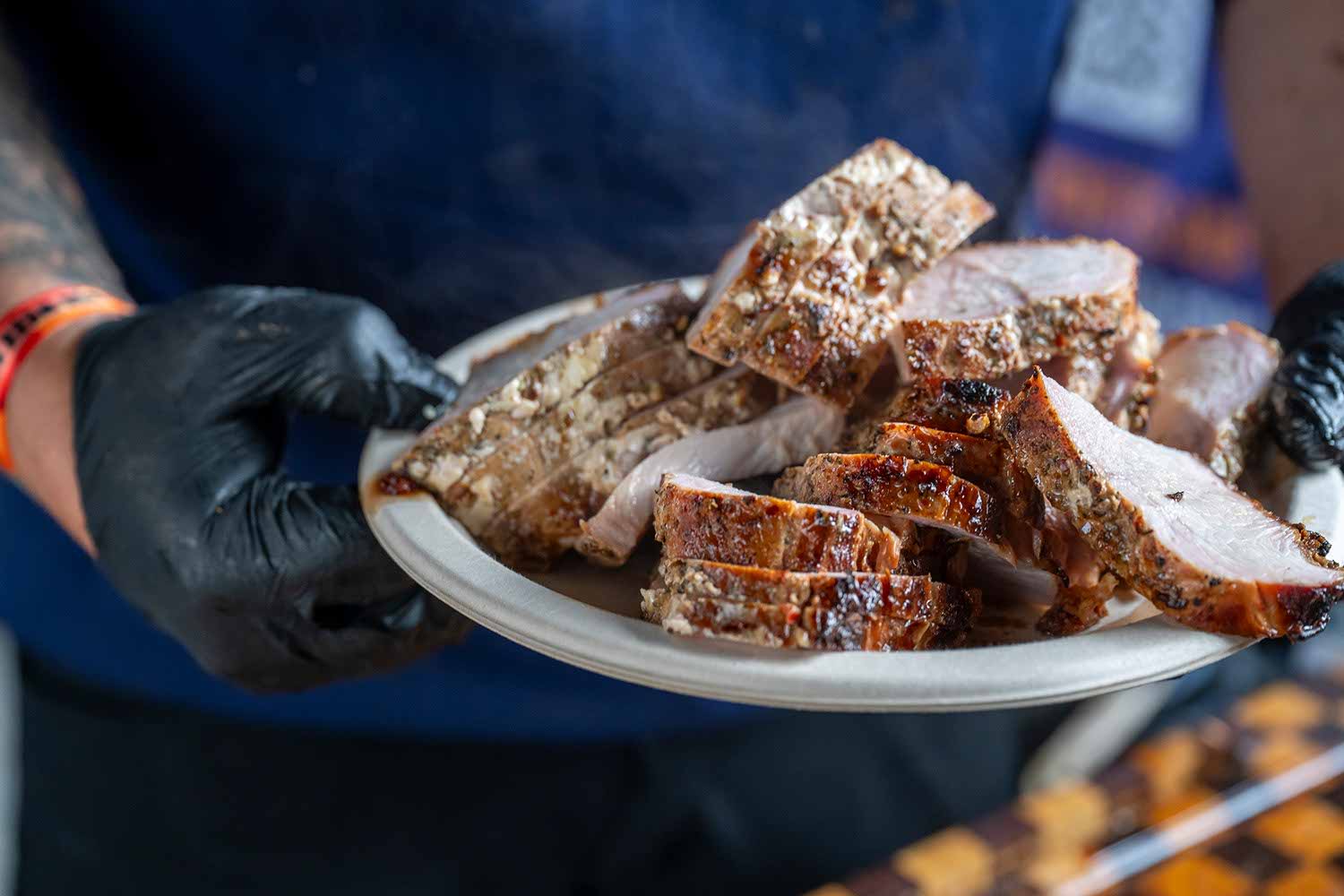 A person holding a plate of sliced meat.
