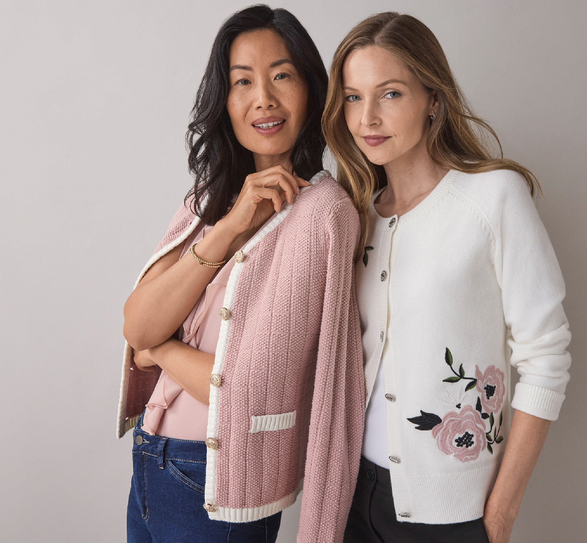 Two women posing together, wearing stylish cardigans.
