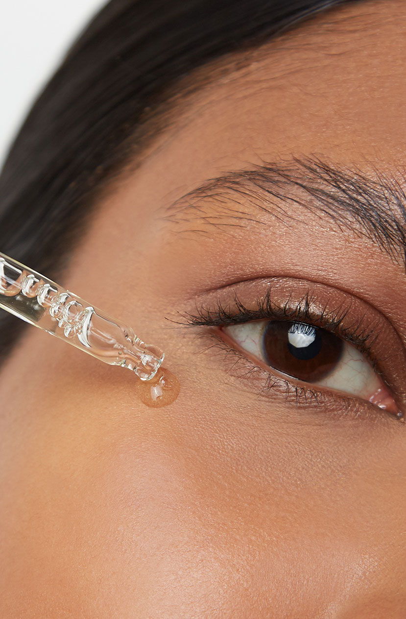 Close-up of a person applying serum near their eye with a dropper.