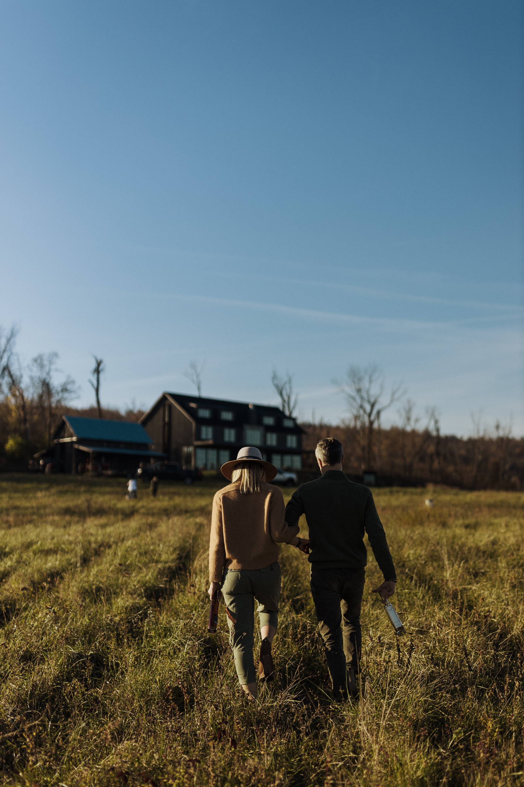 A couple (man and woman) walking towards a large black cabin.
