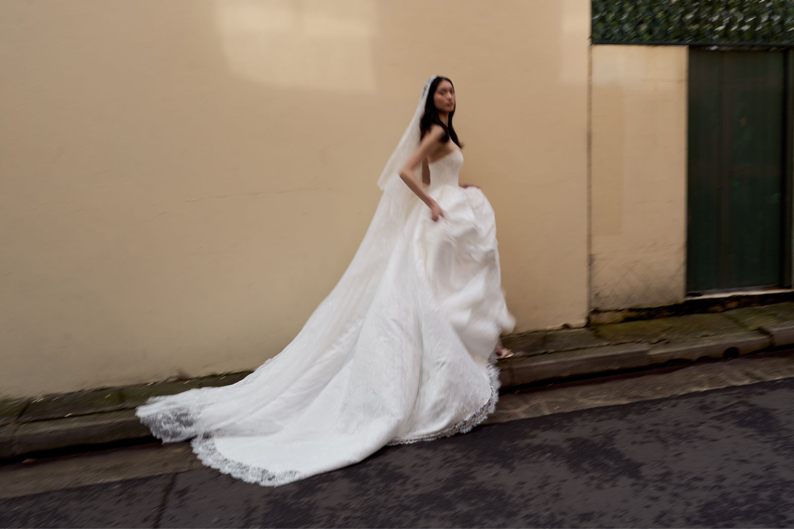 Bride in a flowing white gown walking along a street.