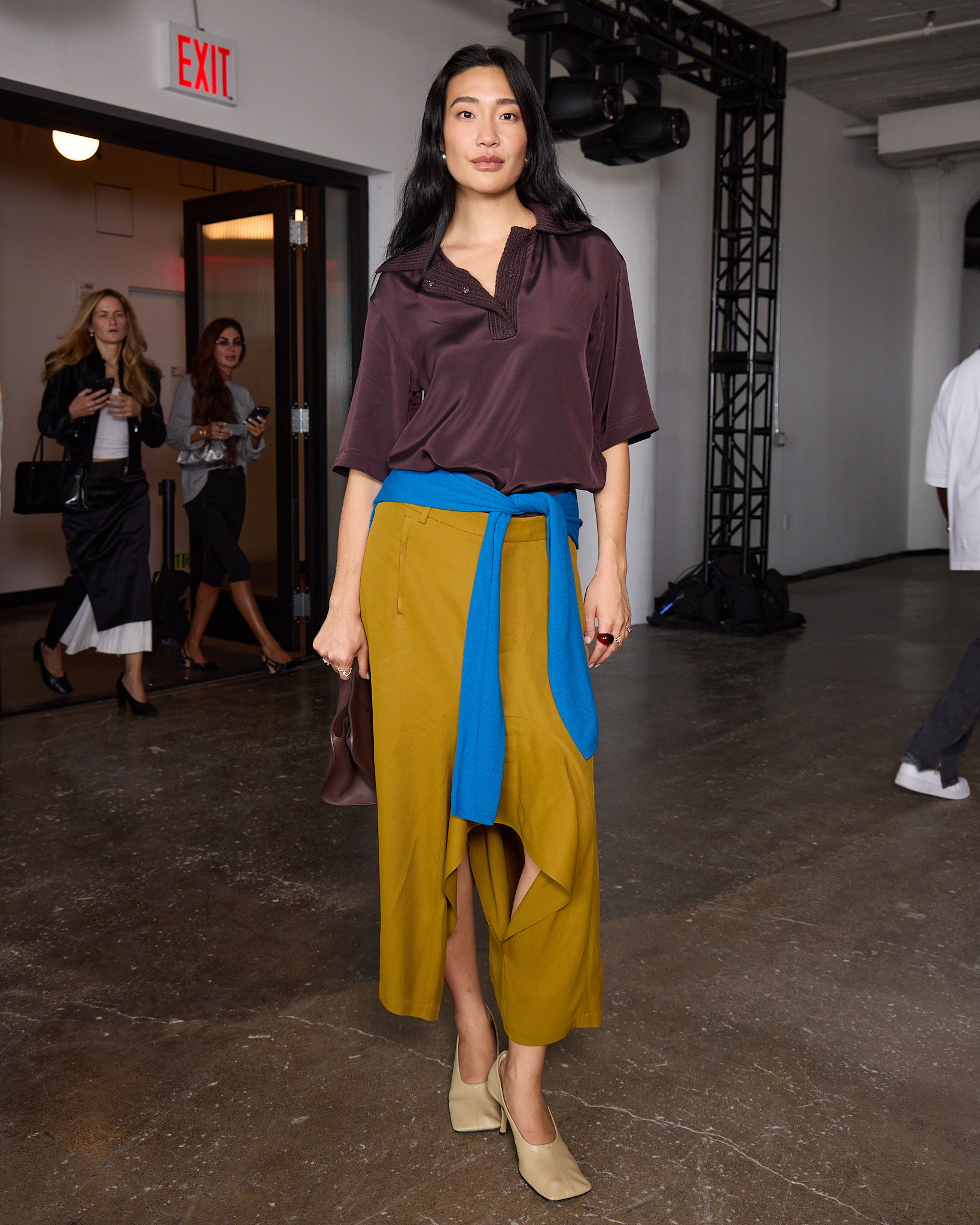 Laura Jung at Tibi new york fashion week runway show wearing a stylish outfit with a brown top and colorful skirt.