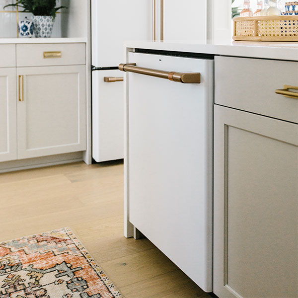 matte white dishwasher in a kitchen designed by Gretchen Black with wooden flooring and decorative rug.