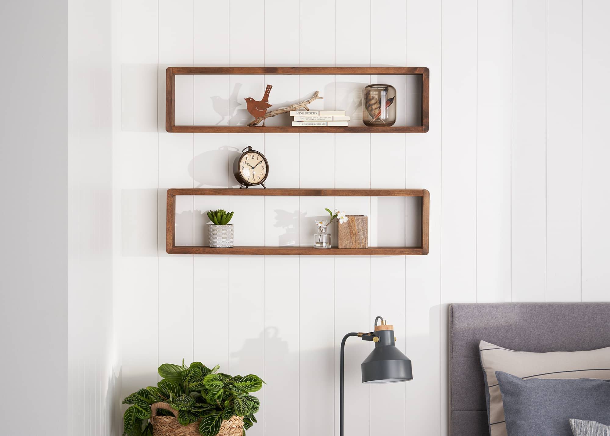 two rectangle wall shelves in a bedroom filled with books and other trinkets