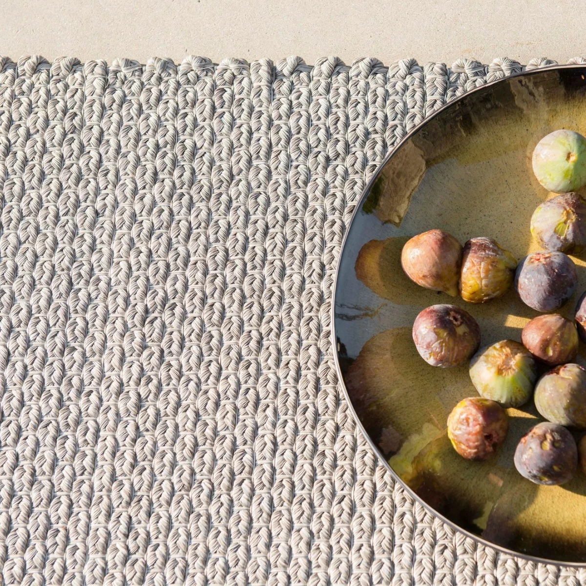 Braided woven outdoor rug in a neutral color with textured construction, showcasing durable synthetic fibers for high-traffic outdoor living spaces. 