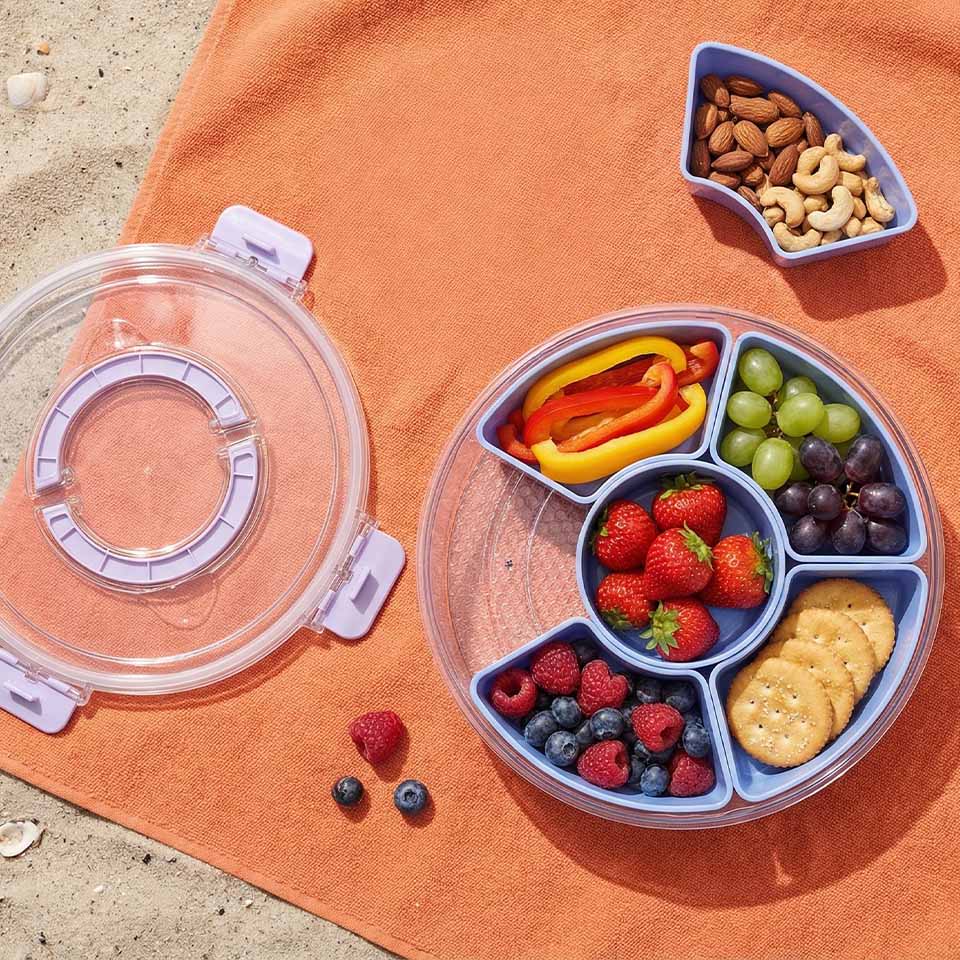 Colorful fruit and nut platter on a beach towel.