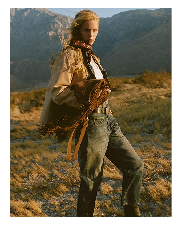 A model poses in a natural landscape wearing casual attire.
