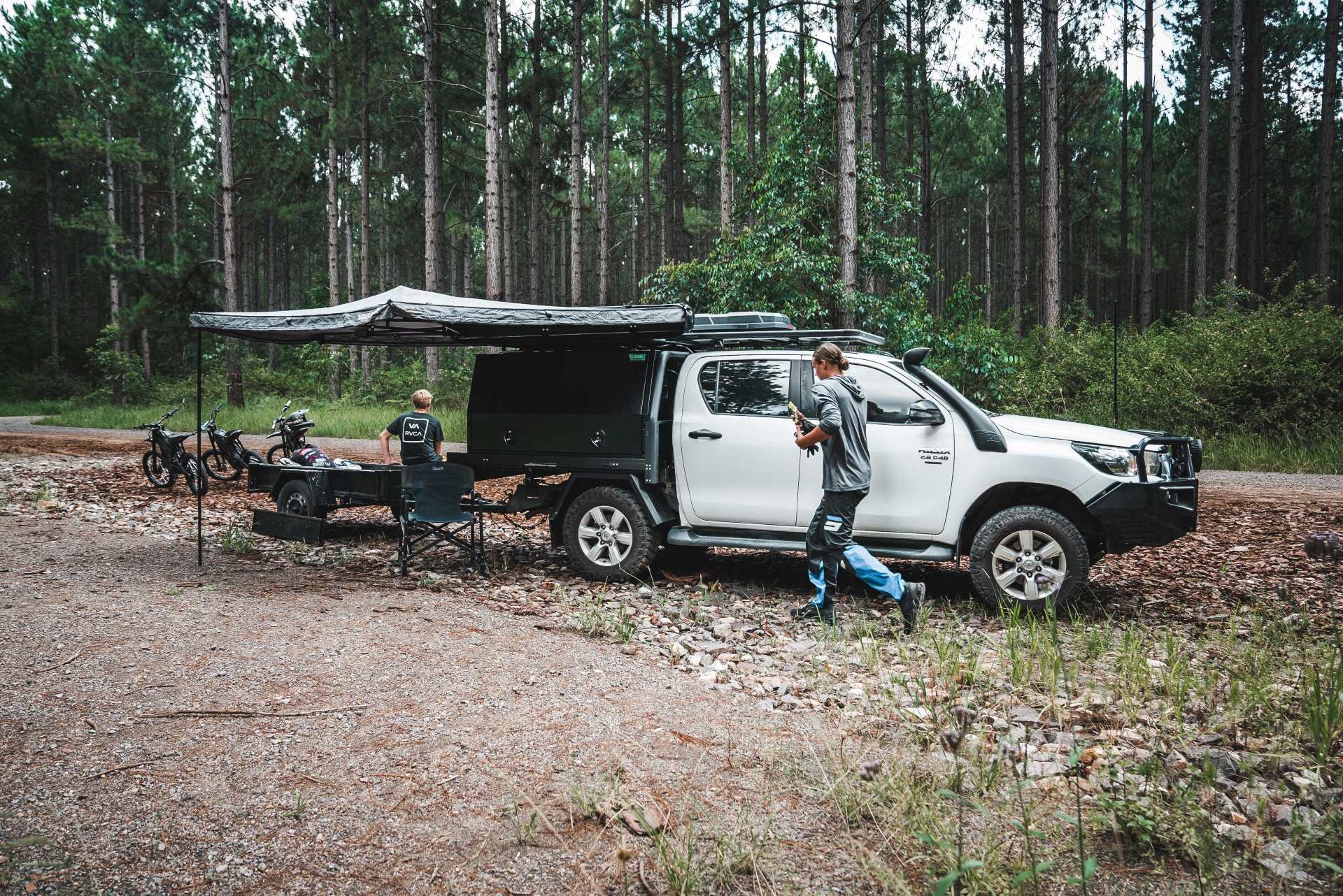 A ute with a custom roof rack and accessories setup, camping with two people