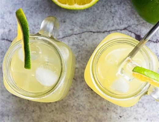 Two mason jars filled with lemonade and garnished with lime slices.