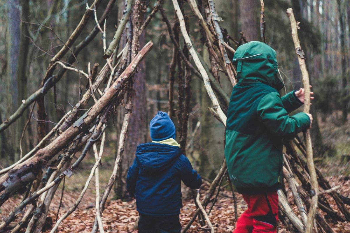 Children laying branches to create a tree-fort in a forest