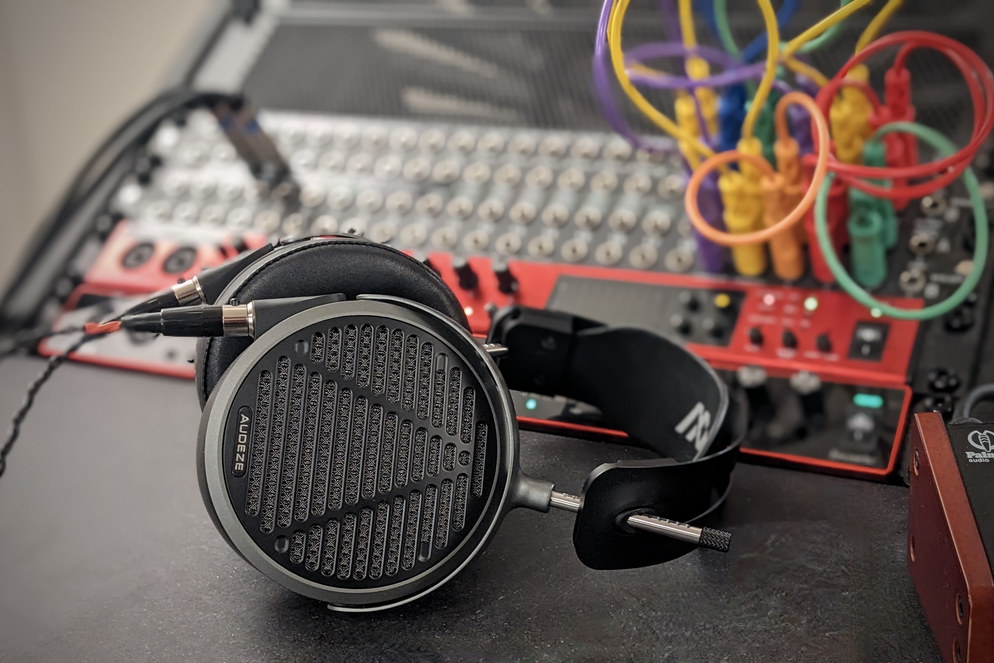 Audeze MM-500 headphones resting on a mixer with colorful cables in the background.