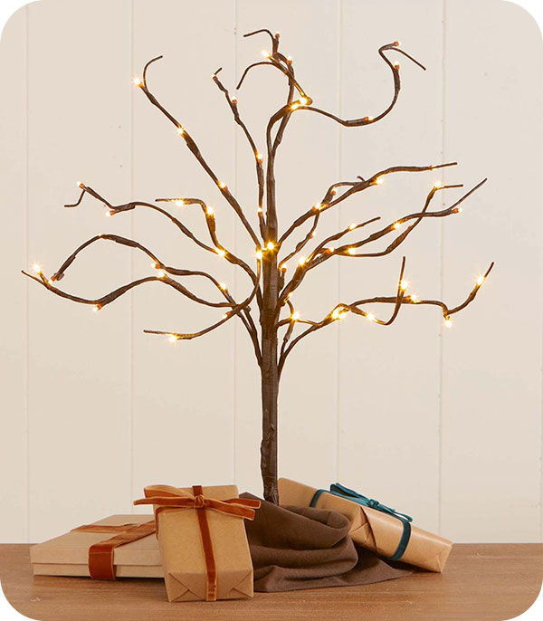 A decorative twig tree with lights and wrapped gifts underneath.